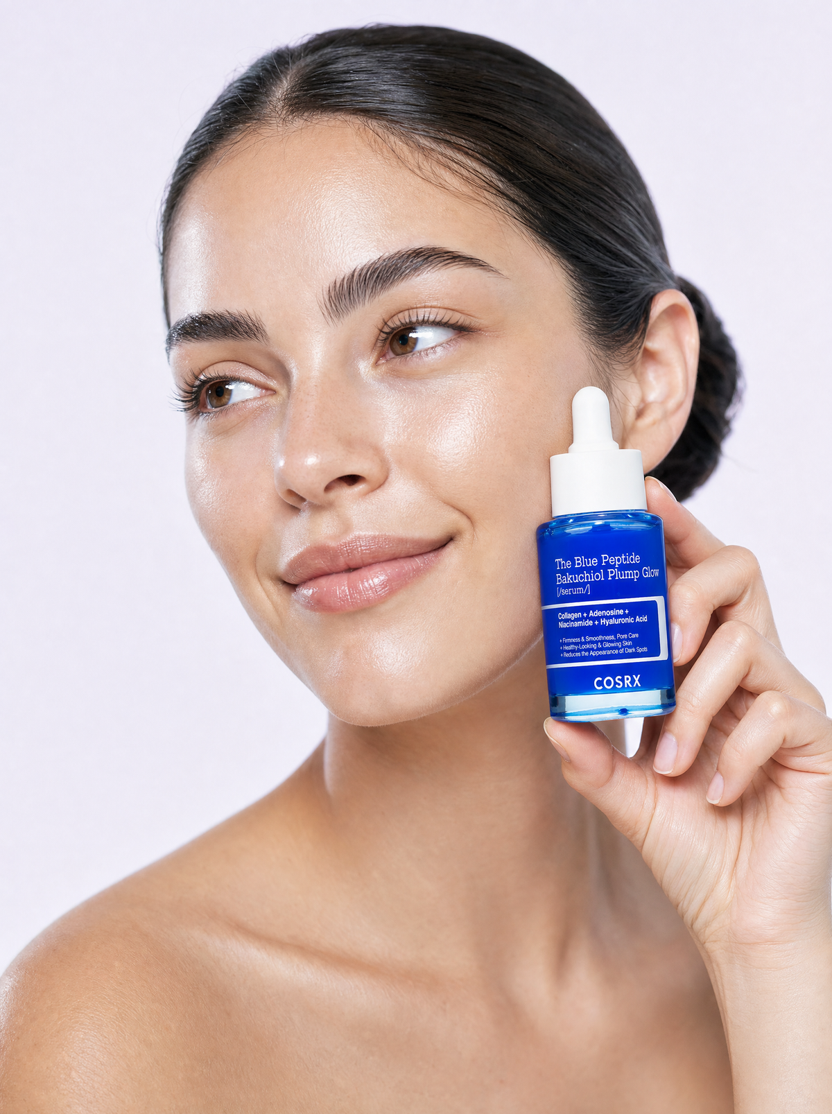 Model holding a peptide serum beside her cheek